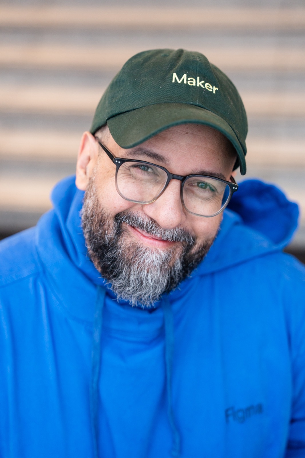 Michel Ferreira, smiling to camera in a green Maker cap and blue Figma hoodie