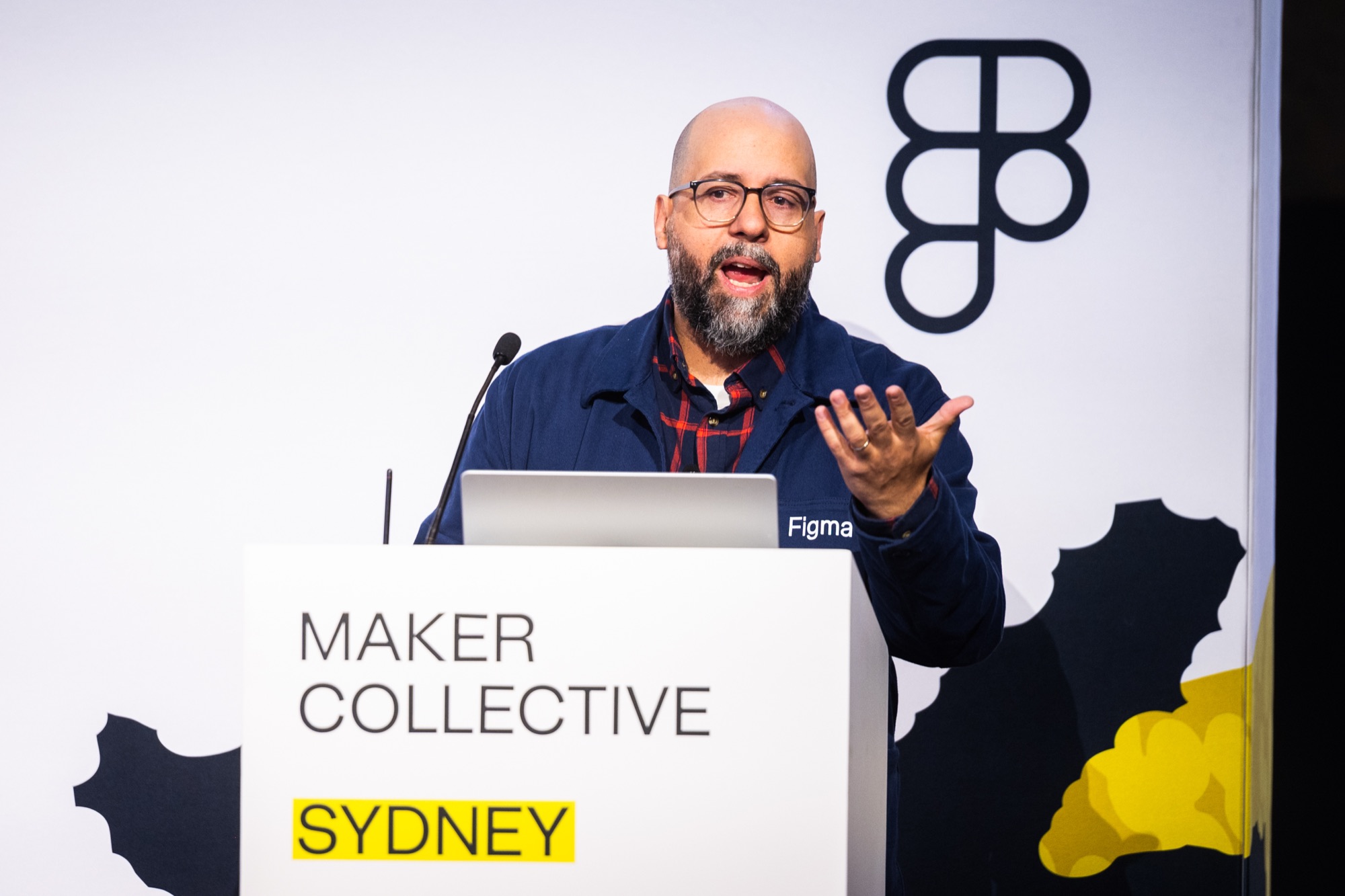 Michel Ferreira speaking at Maker Collective Sydney, laptop with a Figma sticker visible on the podium
